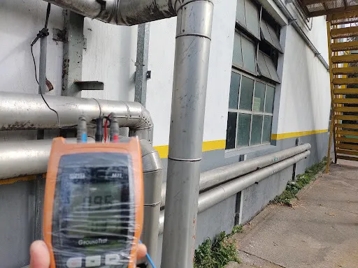 Cañerías de proceso en fachada industrial con telurómetro